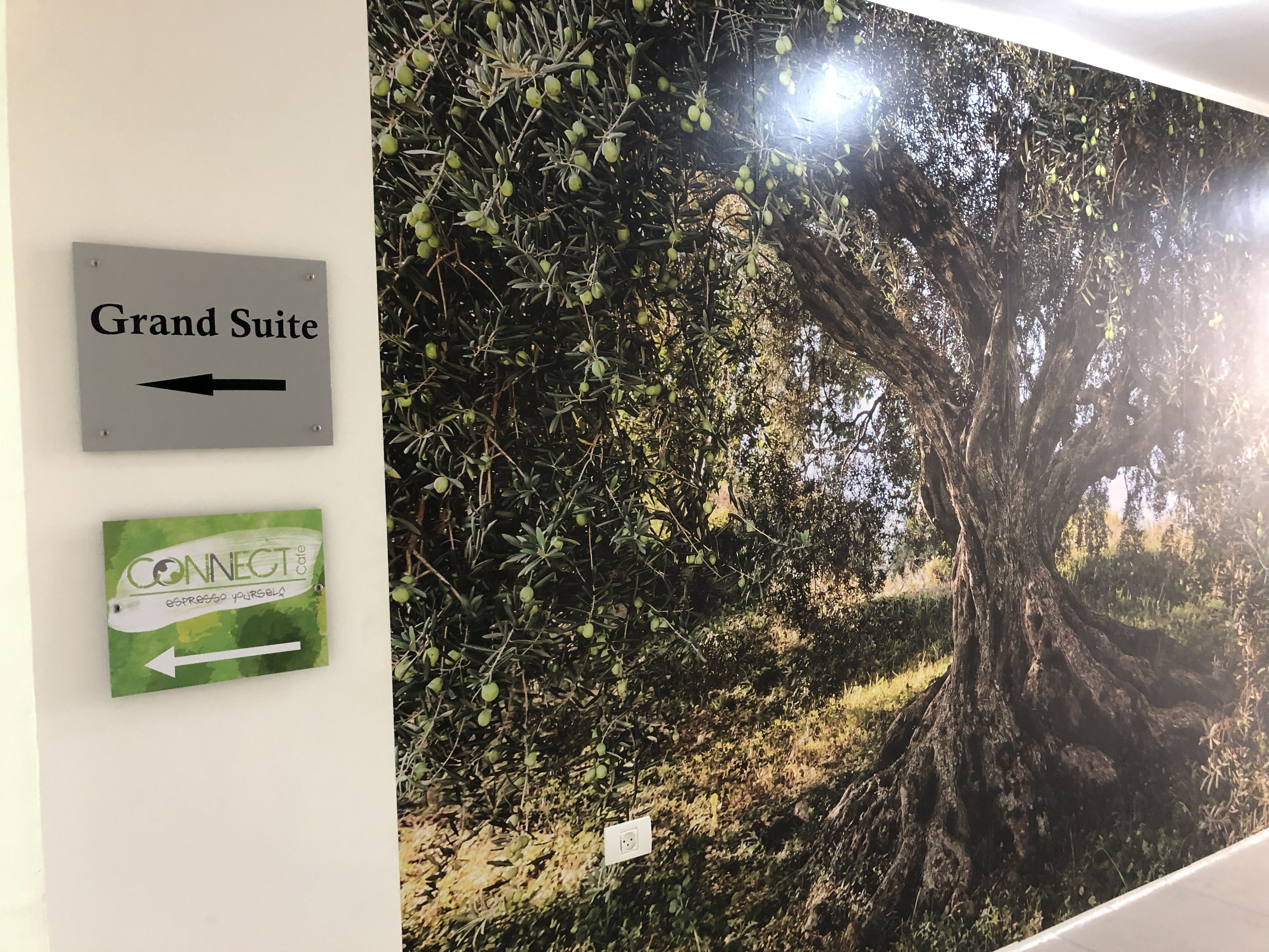 A wall with directional signs for 'Grand Suite' and 'CONNECT Cafe Espresso Yourself'.