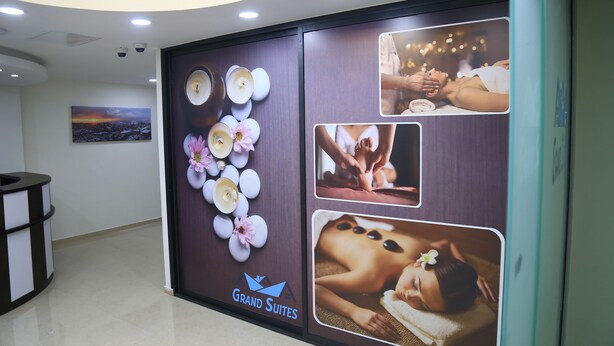 Un pasillo con una recepción, una pared decorada con un arreglo floral y un cartel publicitario de Grand Suites.