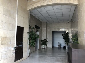 A spacious lobby with a high ceiling, tiled walls, and several potted plants.