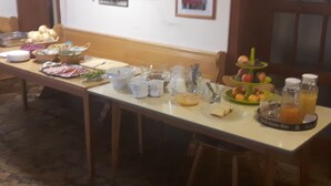 A breakfast buffet table with various food items, cups, and a fruit display. - Gasthaus und Pension Stanek (Hofkirchen)