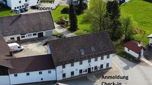 A residential area with multiple houses, a central building labeled "Zimmer Rooms," and a sign for "Anmeldung Check-in." - Gasthaus und Pension Stanek (Hofkirchen)
