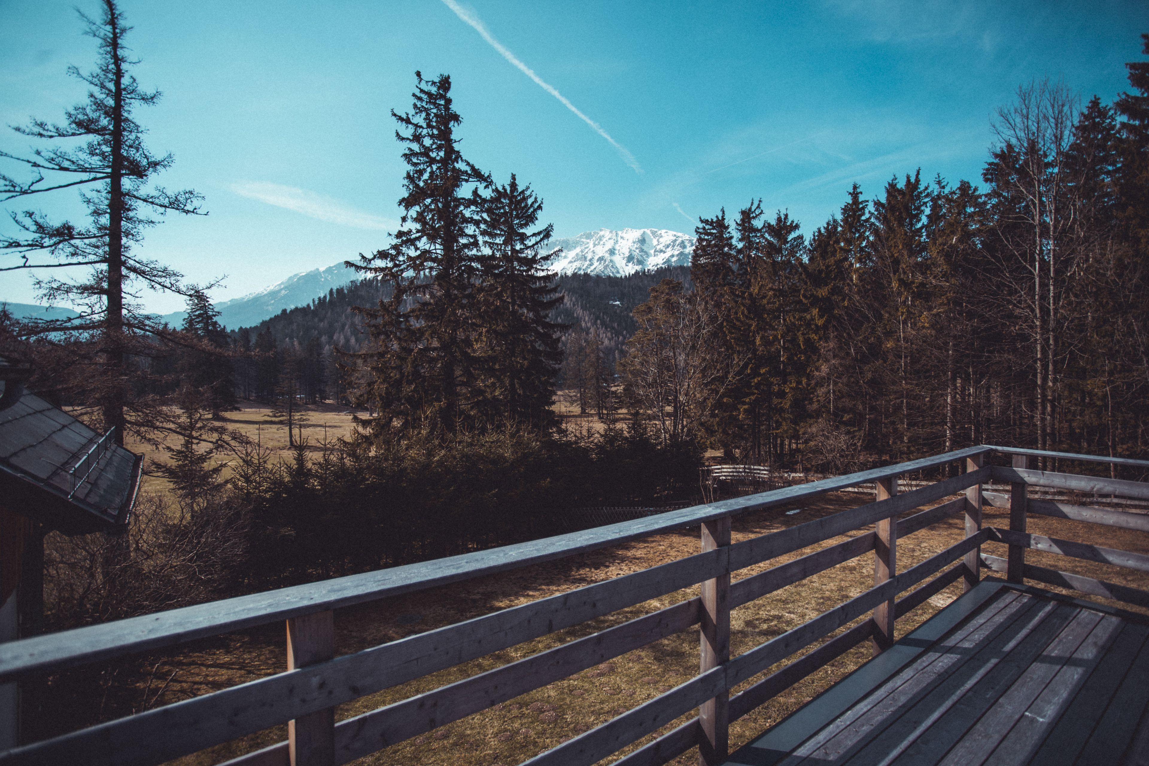 Eine Holzterrasse mit Blick auf einen Wald und ein Gebirge.