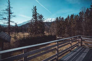 Eine Holzterrasse mit Blick auf einen Wald und ein Gebirge.