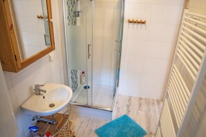 Ein Badezimmer mit Waschbecken, Duschkabine aus Glas und Handtuchhalter.