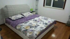 Un dormitorio con cama, mesita de noche y ventana.