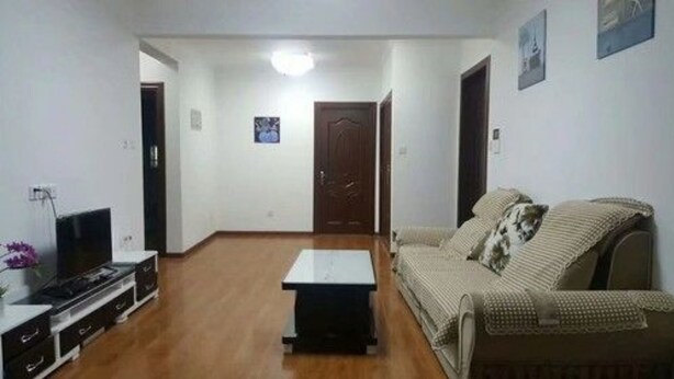 Una sala de estar con un sofá, una mesa de centro, un televisor y una puerta.