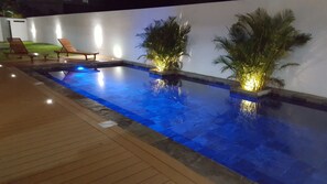 An outdoor swimming pool with two palm trees and a wooden deck. - Blue Lagoon Flic en Flac (Flic-en-Flac)