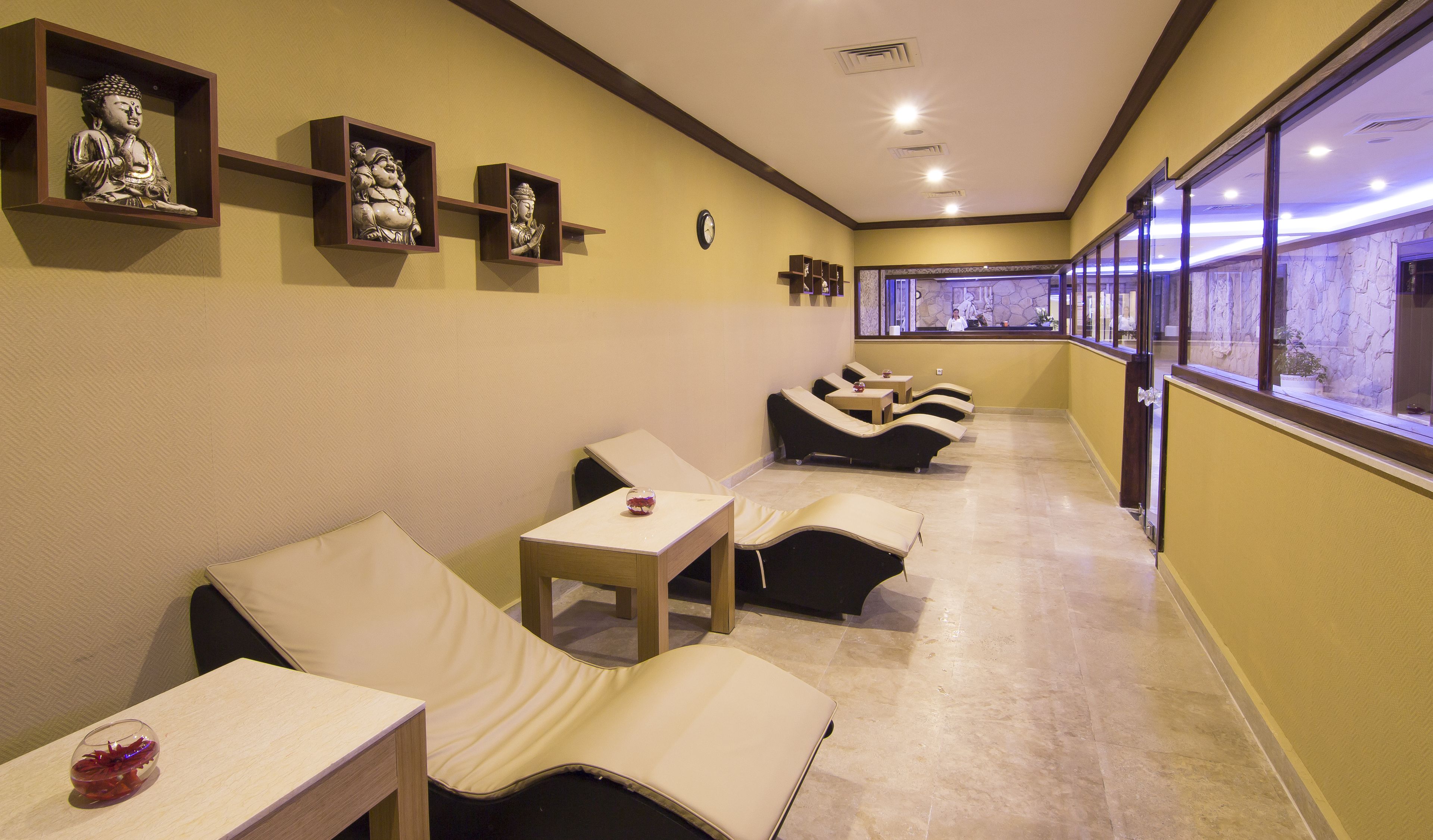 Un cuarto de spa con sillones reclinables, un reloj y estatuas en la pared.