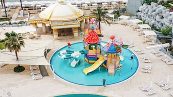 A water park with a large slide, play structures, and lounge areas with umbrellas.