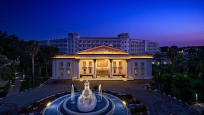 Un hotel elegante con una fuente central, arquitectura simétrica y un jardín bien cuidado.