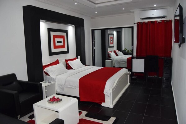 A modern hotel room with a large bed, a desk, and a chair. - Miliet Hotel (Abidjan)