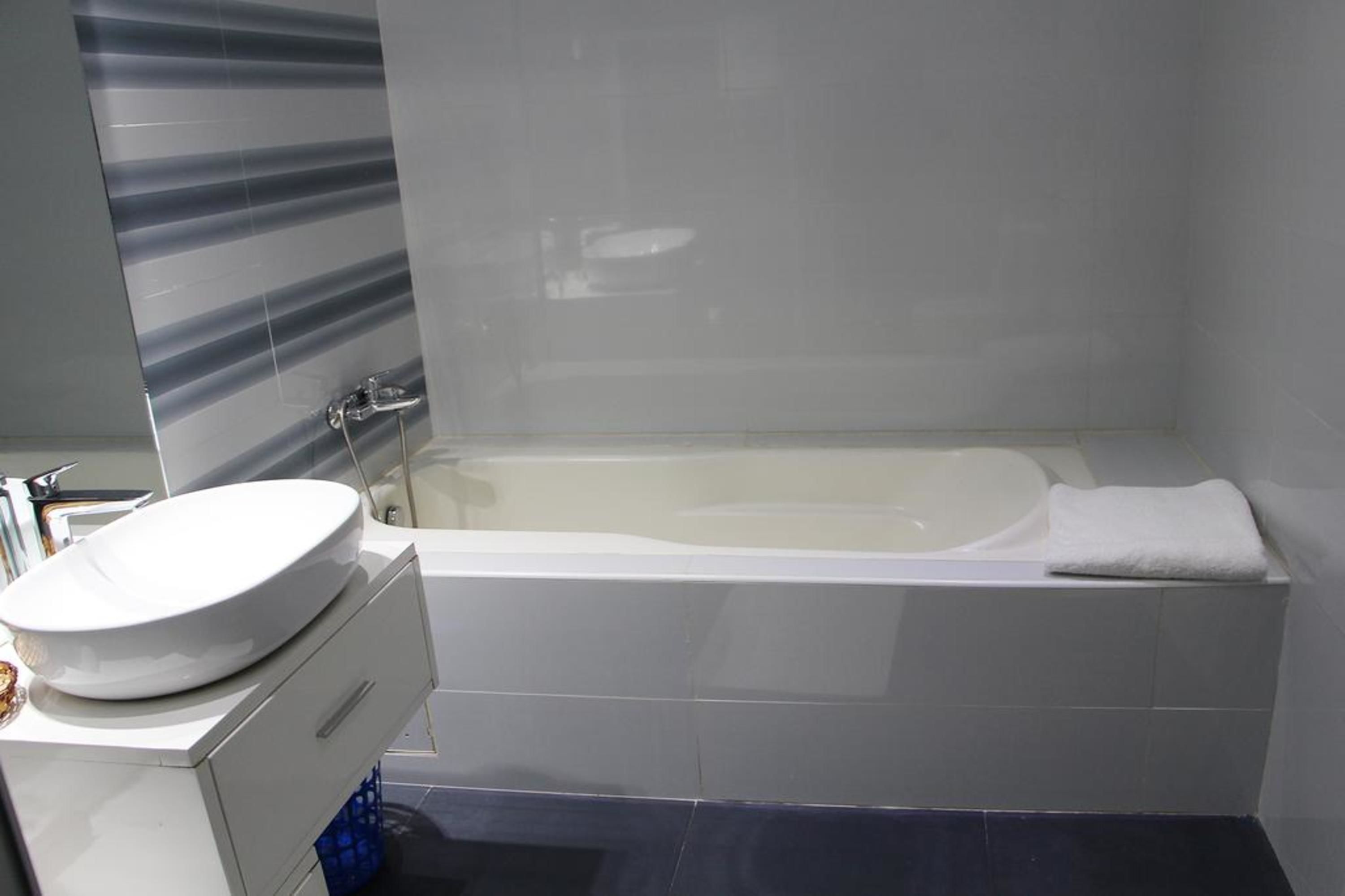 Une salle de bain moderne avec une baignoire sur pieds, un lavabo blanc et un miroir.