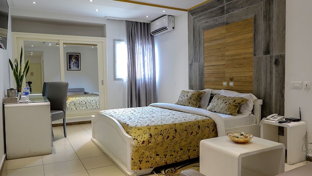 A modern bedroom with a bed, bedside table, and a desk with a chair. - Miliet Hotel (Abidjan)