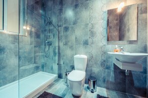A modern bathroom with a glass-enclosed shower, a white toilet, and a sink with a mirror above it. - Charming Seafront Apartment, Perfect for Families (Sliema)