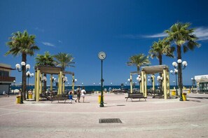 A public square with a clock, palm trees, benches, and lamp posts. - Luxury 2 Bedroom Apartment by the Sea (St. Paul's Bay)