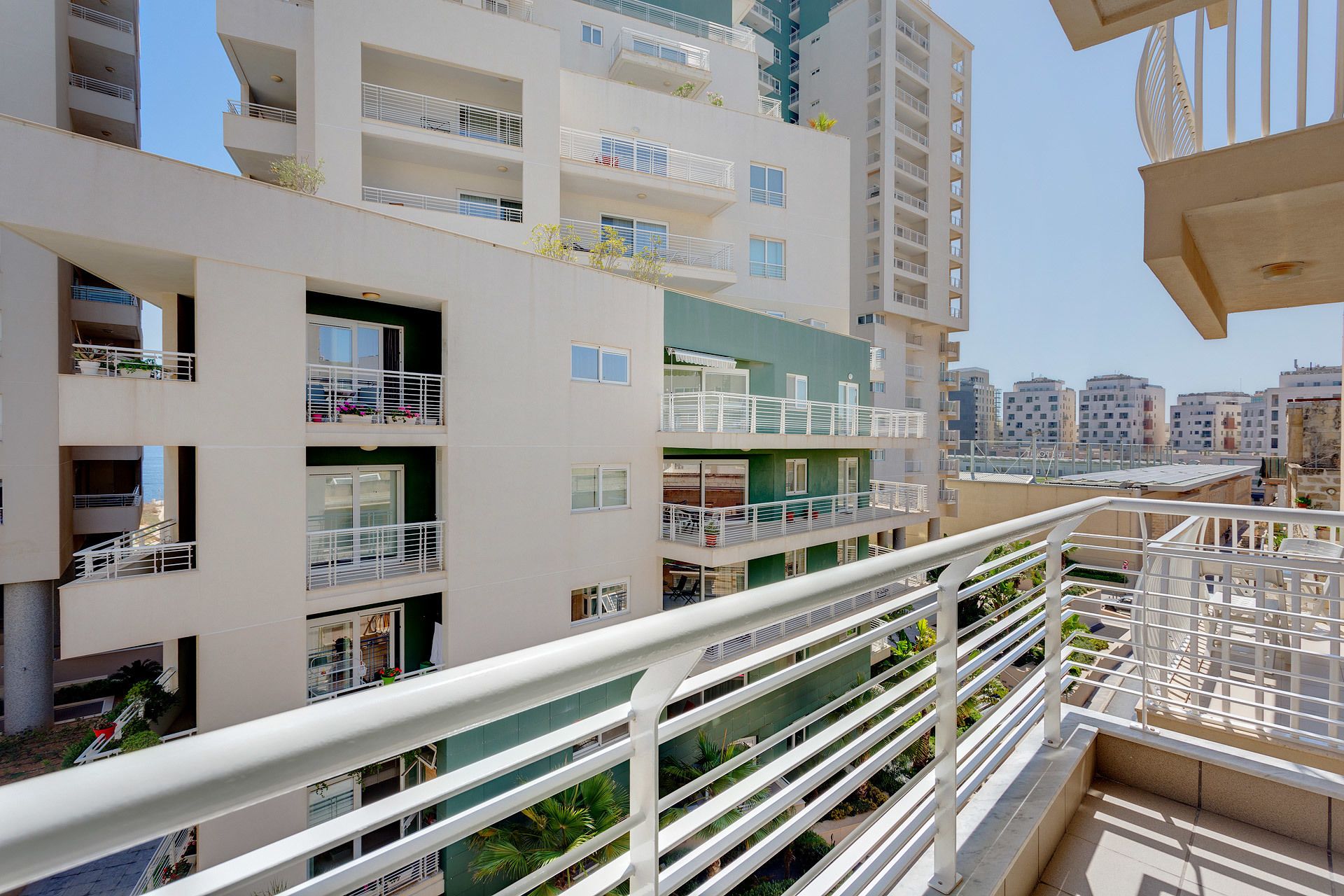 A multi-story residential building with balconies, a rooftop terrace, and a view of the cityscape.