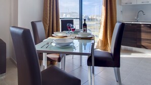 Een moderne eethoek met een glazen tafel, zwarte stoelen en uitzicht op de stad door grote ramen.