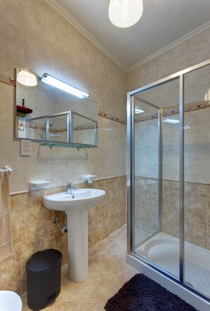 A modern bathroom with a glass shower enclosure, a pedestal sink, and a mirror above the sink. - Modern Apt Overlooking Green Area (St. Paul's Bay)