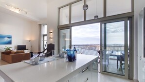 A modern kitchen with a large island, a dining area with a view, and a living room with a TV and seating. - Marvellous Apartment in Tigne Point With Pool (Sliema)