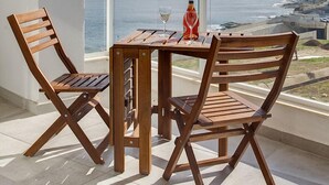 A balcony with a wooden table and chairs, a bottle of wine, and a glass, overlooking a coastal view. - Marvellous Seafront Apartment in the Best Location (Sliema)