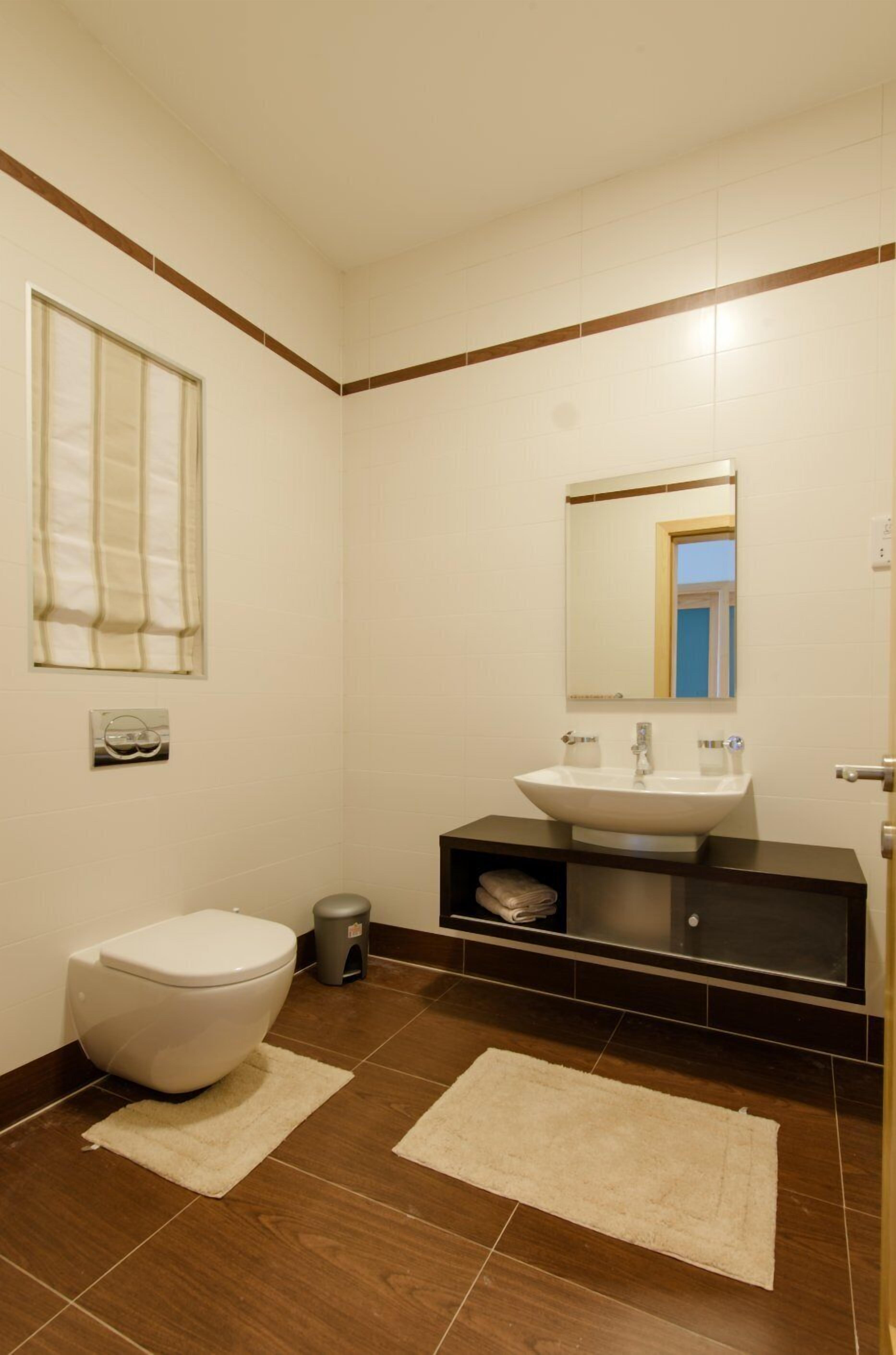 Ein Badezimmer mit Toilette, Waschbecken, Spiegel und einem Fenster mit Vorhängen.
