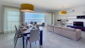 Ein modernes Wohnzimmer mit Essbereich, einer Couch, einem Fernseher und einem Balkon mit Blick.
