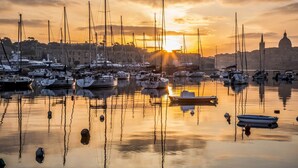 A marina with multiple boats docked, a prominent dome structure in the background, and calm water reflecting the sunset. - Seaview APT Incl Pool IN Sliema (Sliema)
