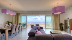 A modern hotel room with a dining area, a sofa, and a view of the ocean. - Seaview APT Incl Pool IN Sliema (Sliema)