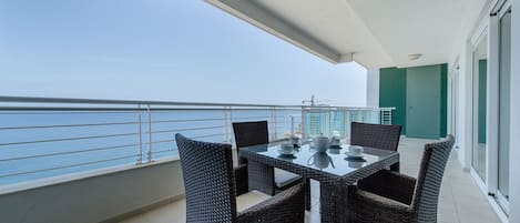 A balcony with a table and chairs, overlooking a body of water.