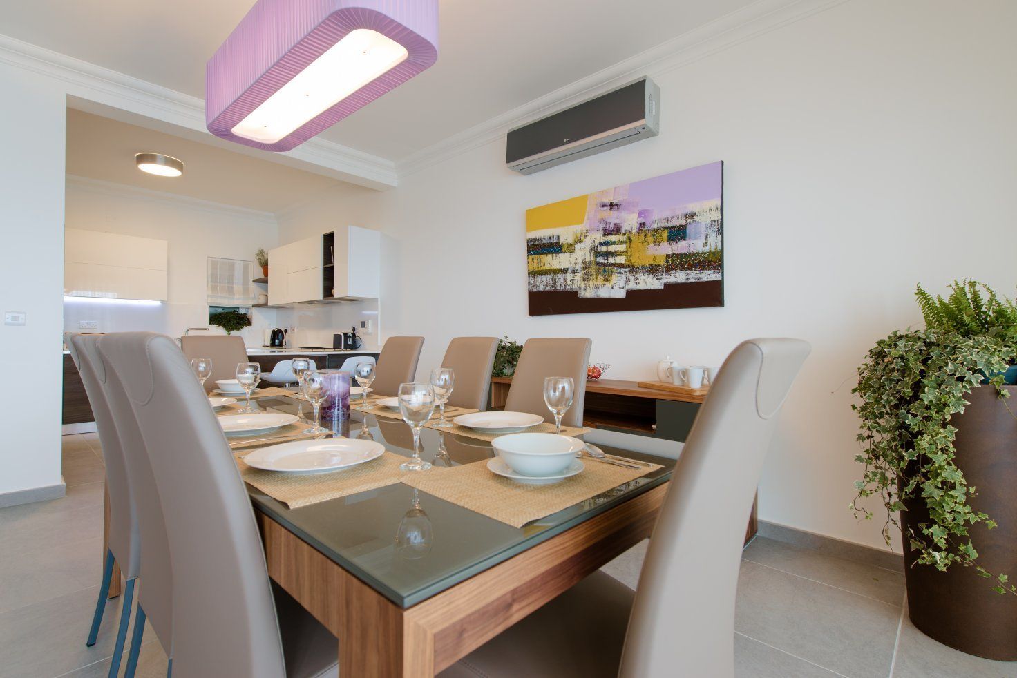 A dining area with a wooden table set for six, surrounded by beige chairs.