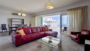 A spacious living room with a red leather sofa, a glass coffee table, and a dining area with a table and chairs. - Seafront Lux Fort Cambridge wt Pool (Sliema)