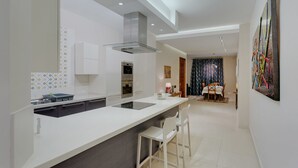 Uma cozinha moderna com ilha central, forno embutido e área de refeições com mesa e cadeiras.