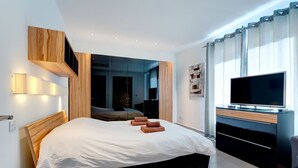 A modern hotel room with a large bed, a flat-screen TV, and a mirror. - Seaview Apartment In Fort Cambridge, Sliema (Sliema)