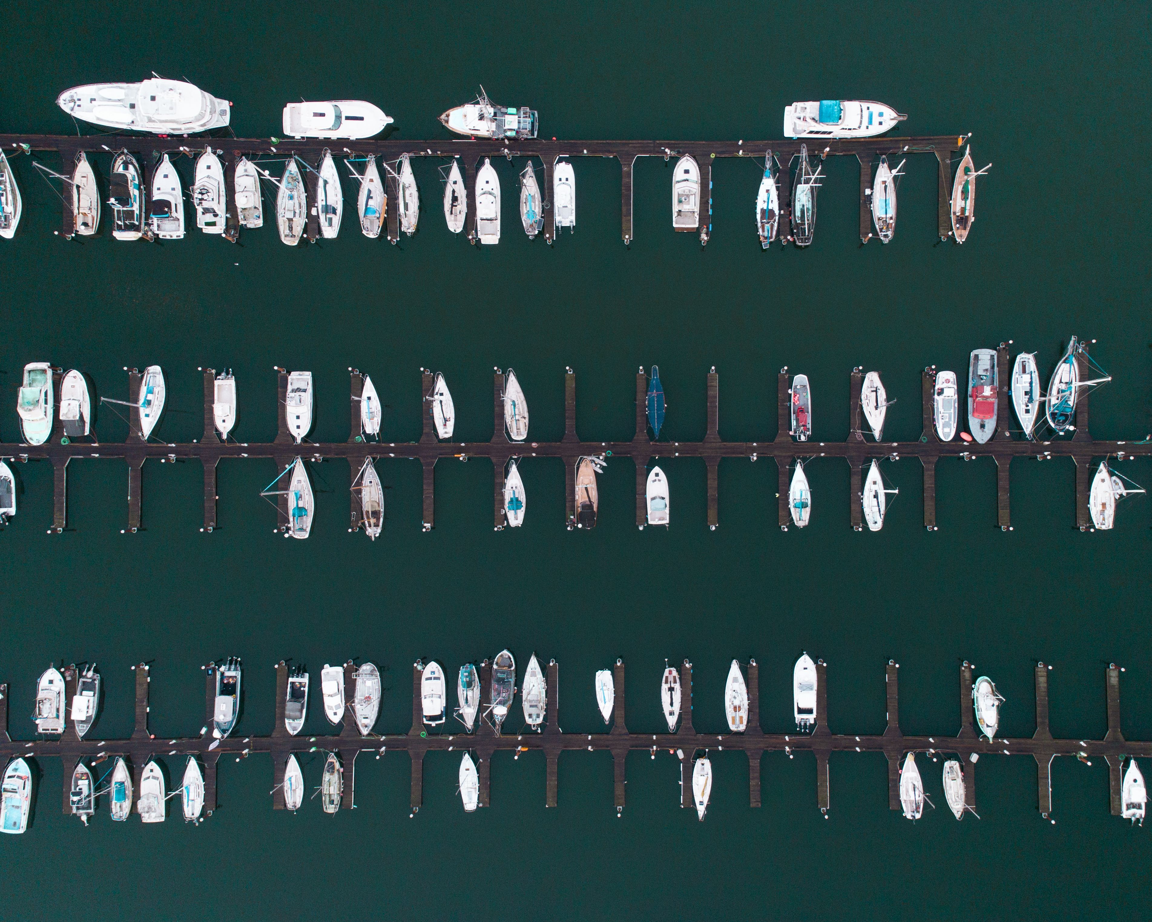 Vista aérea de un puerto deportivo con numerosos barcos amarrados en un diseño ordenado.