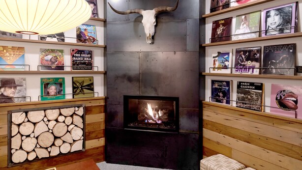 A cozy room with a fireplace, wooden shelves with books and framed pictures, and a large bull skull decoration. - Norblad Hotel (Astoria)
