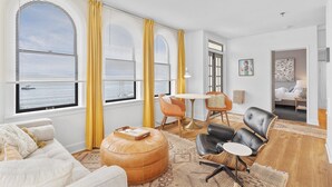 A spacious living room with large windows, a cozy seating area, and a view of the water. - Norblad Hotel (Astoria)
