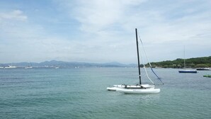 Un puerto tranquilo con un velero en primer plano y varios barcos en el fondo.
