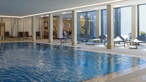 An indoor swimming pool with lounge chairs and a sun terrace. - Hotel Schnitterhof (Bad Sassendorf)