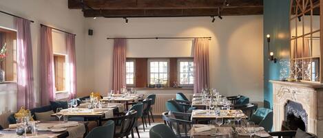 A restaurant with multiple tables set for dining, wooden beams on the ceiling, and large windows with curtains.