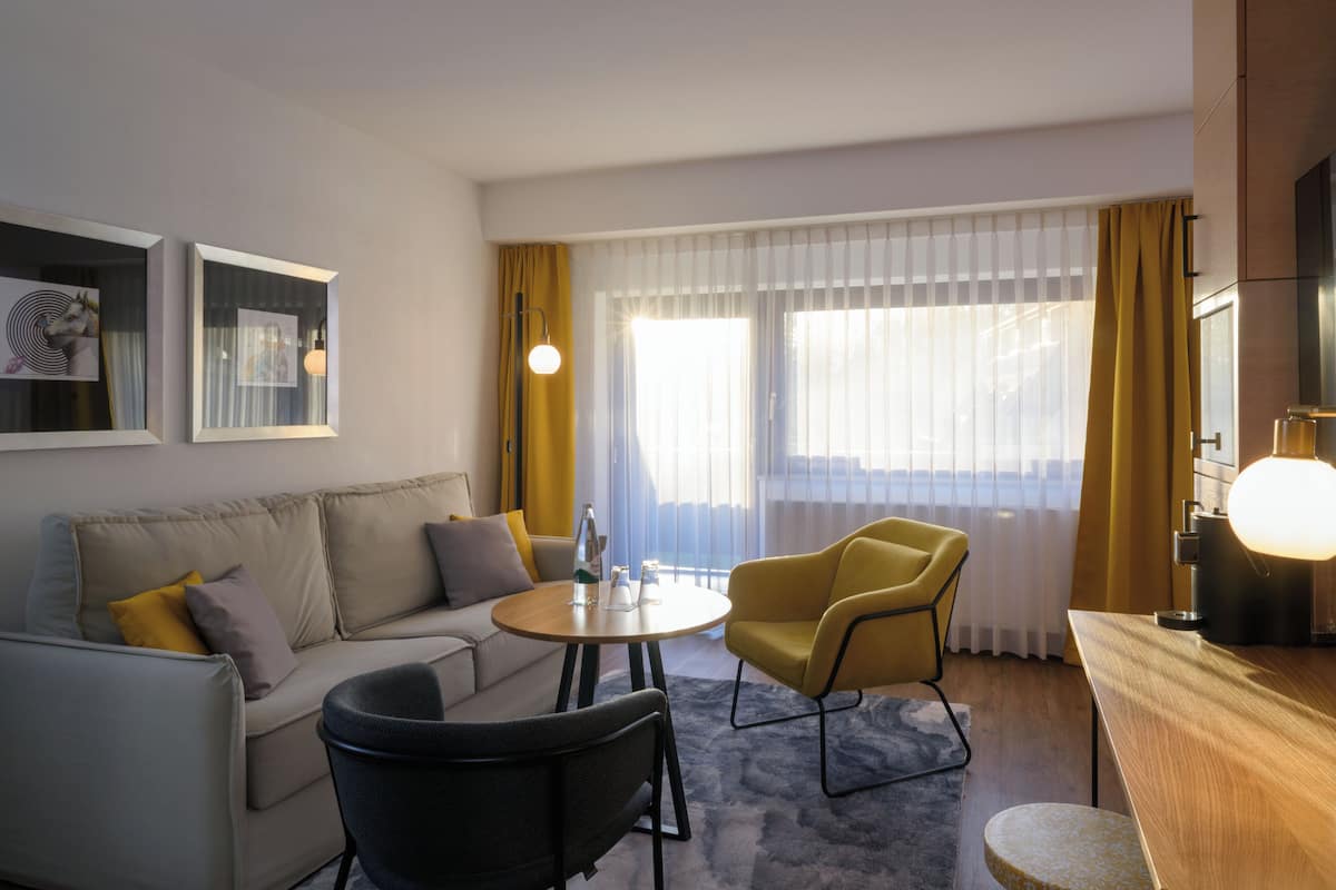Un salon moderne comprenant un canapé, deux fauteuils, une table basse ronde et un téléviseur.