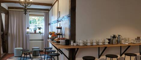 A kitchen with a wooden bar, stools, and a variety of breakfast items.