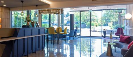 A modern interior with a reception desk, seating area, and large windows offering a view of the outdoors.
