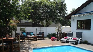 A backyard with a swimming pool, wooden deck, and outdoor furniture. - Inn2Wilderness Guesthouse (Wilderness)