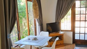 A dining area with a table, chairs, and a television. - Inn2Wilderness Guesthouse (Wilderness)