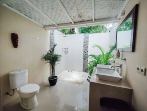 A bathroom with a toilet, sink, and shower area. - Ekas Surf Resort (Jerowaru)