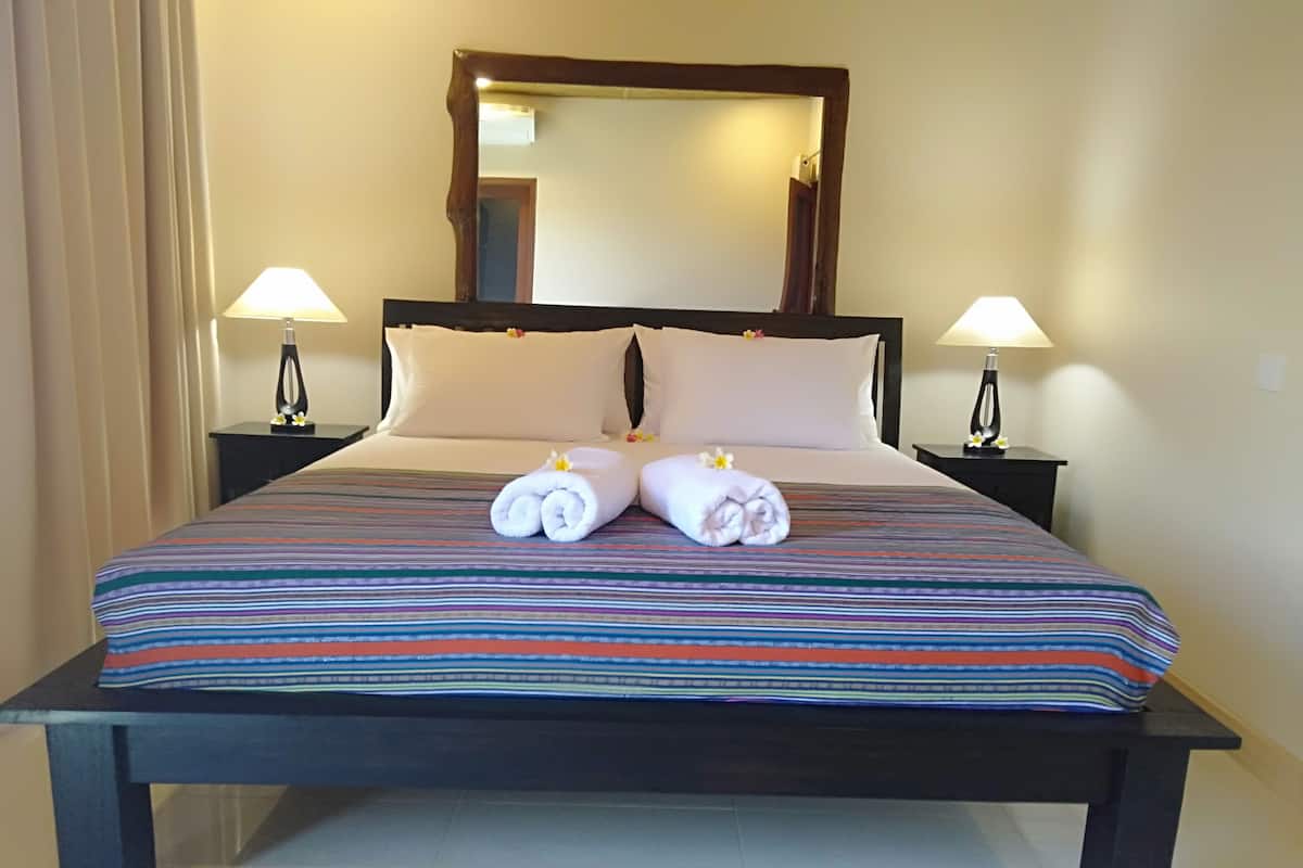 Une chambre d’hôtel avec un grand lit, deux lampes de chevet, un miroir au-dessus du lit et une paire de serviettes posées sur le lit.