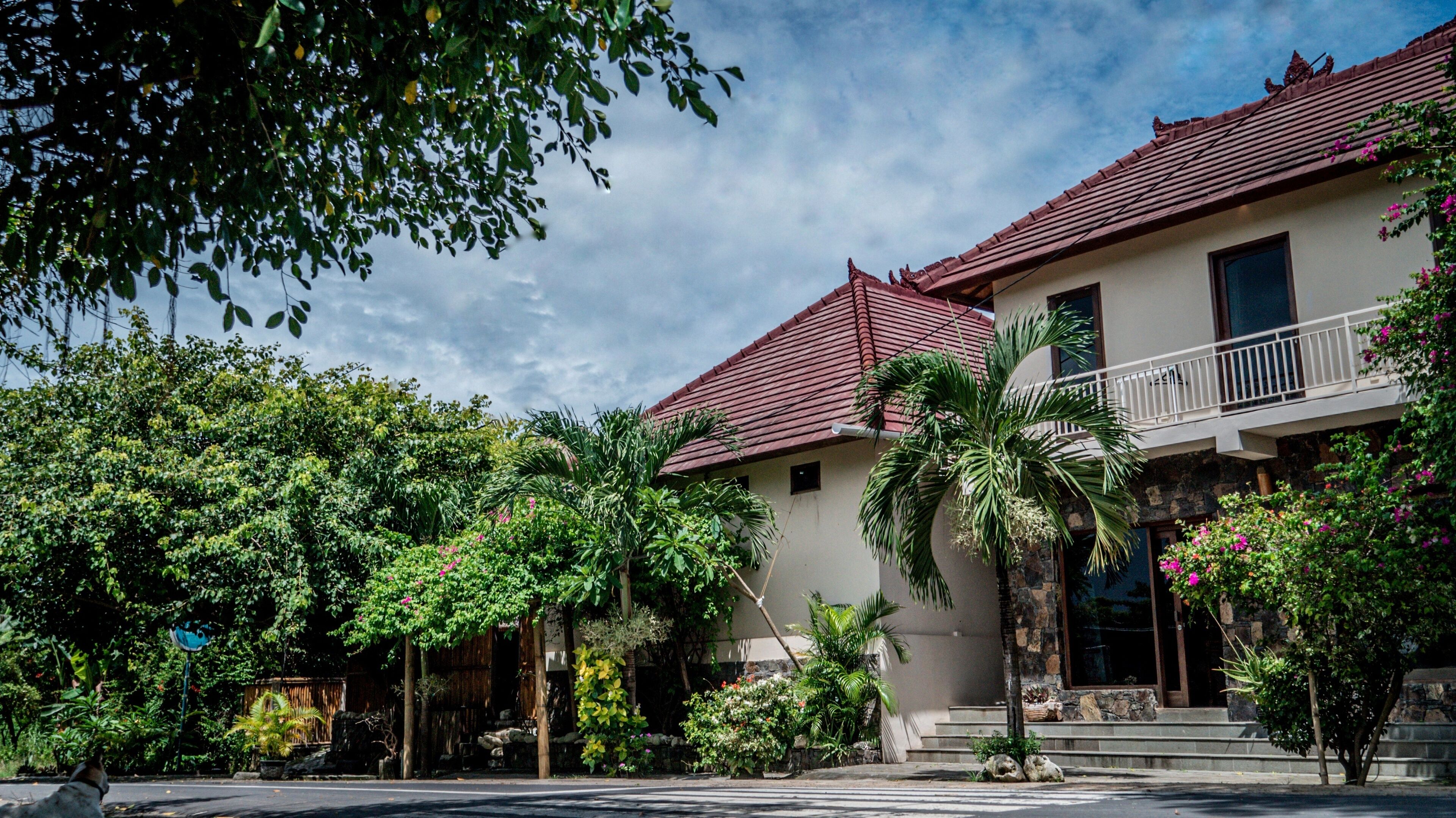 A two-story building with a red-tiled roof, a balcony, and a stone facade.