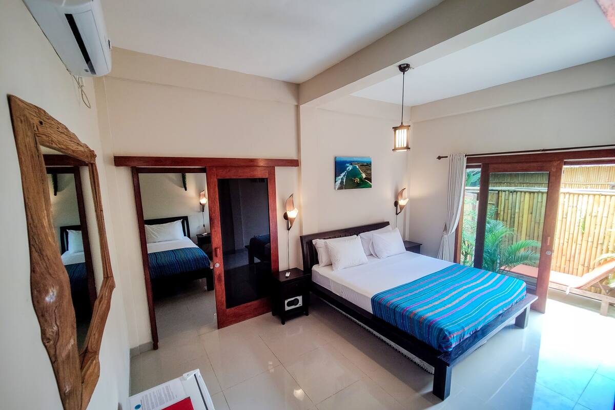 Une chambre d’hôtel avec un grand lit, une porte en bois, une petite table et une vue sur l’extérieur.
