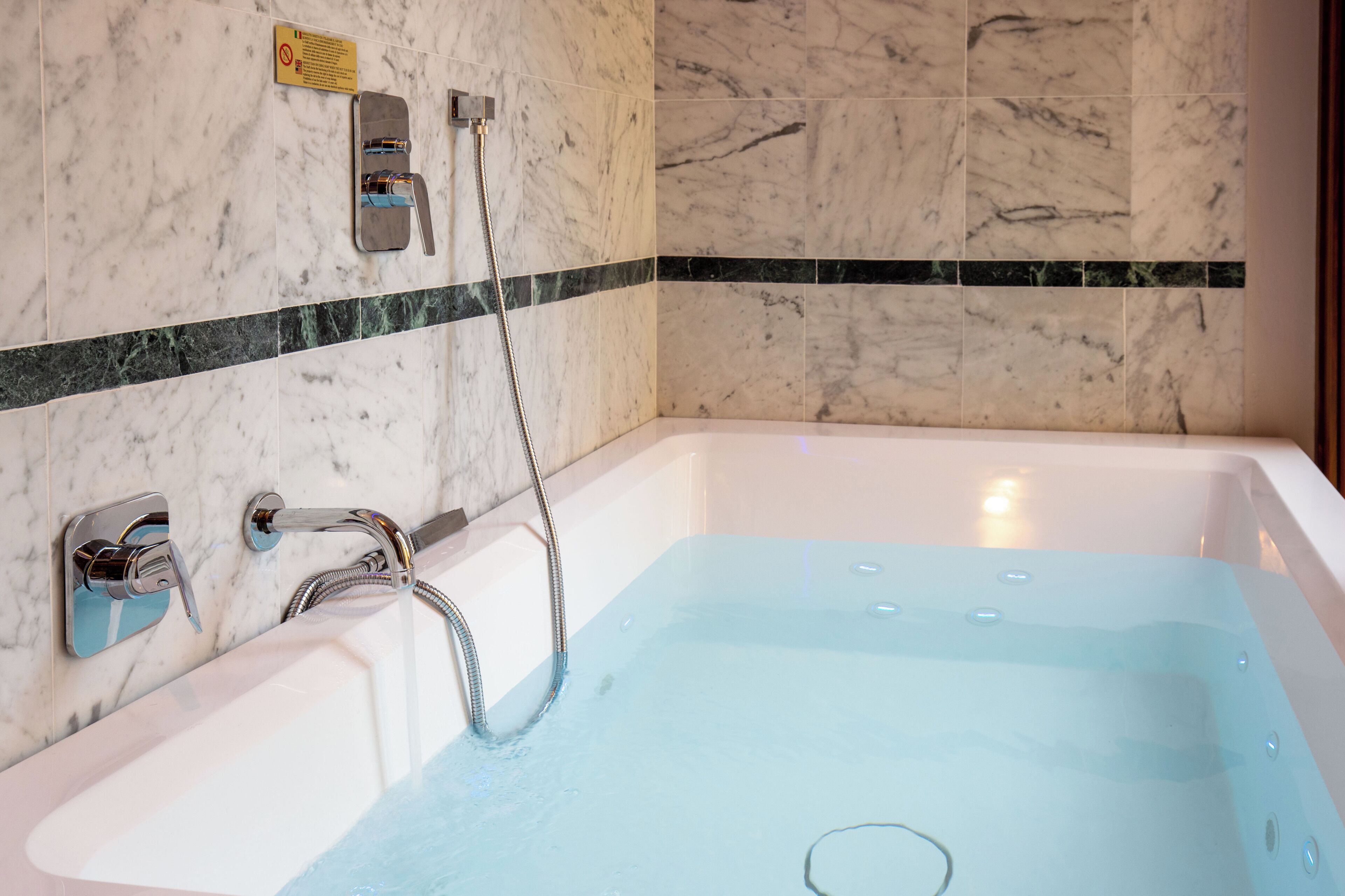 Een moderne badkamer met een marmeren wand, een badkuip en een douche.