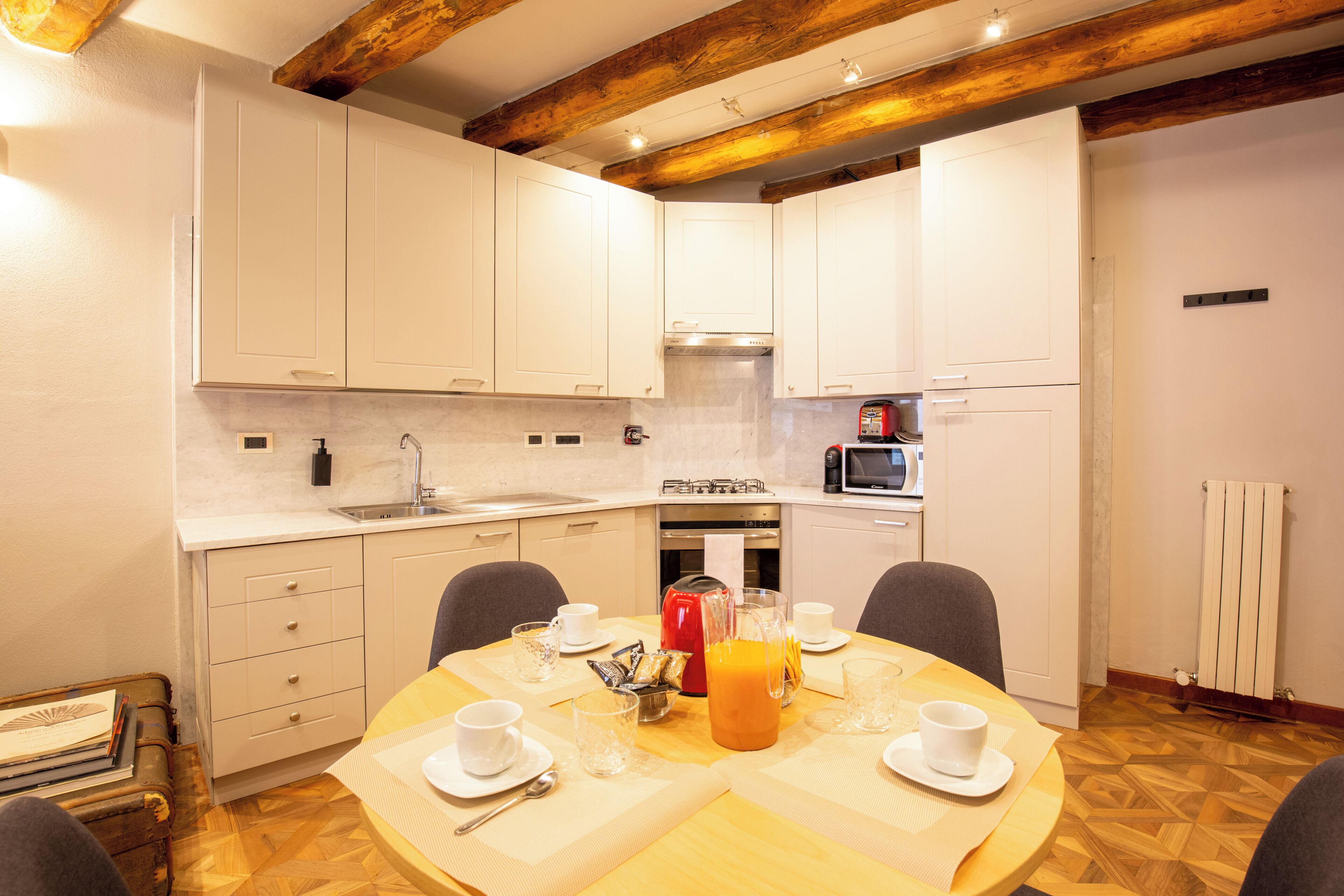 A modern kitchen with white cabinets, a wooden ceiling, and a dining area with a table set for two.